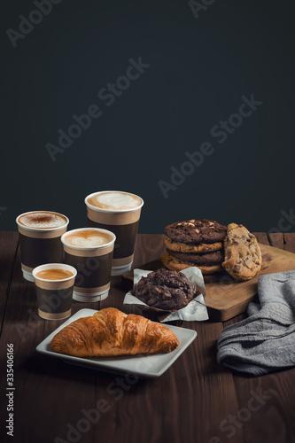 four types of coffee, espresso, cappuccino, latte and mokiyato in disposable take-away cups with pastries on one table, croissant and chocolate shortbread cookies. poster ready to print