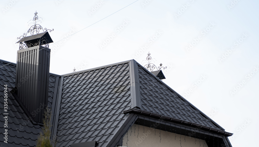 Black metal tile roof. Roof metal sheets. Modern types of roofing materials. Roof of the house, metal roof tile against the blue sky. Building.