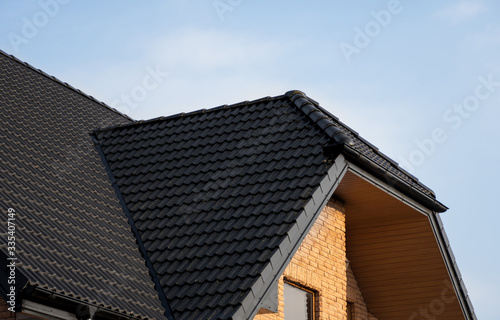 Brown metal tile roof. Roof metal sheets. Modern types of roofing materials. Roof of the house, metal roof tile against the blue sky. Building. © Volodymyr