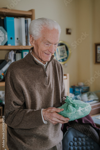 Cheerful senior holding home-delivered meal, quarantine during pandemic Covid-19