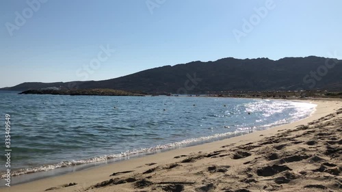 Turquoise sea on a sandy beach with mountains and blue sky in background in a sunny day in Greece. photo