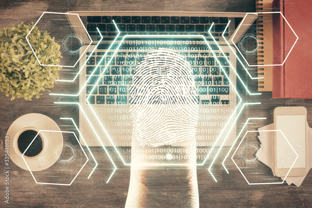 Obraz premium Finger print over computer on the desktop background. Top view. Double exposure. Concept of securitization.