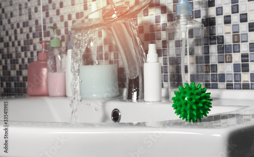 Canvas Print The green covid-19 coronavirus molecule sits on the white washstand in the bathroom