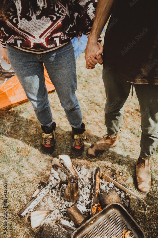 Obraz premium stylish young couple of travelers. Family on a walk in the mountains laid out a tent, prepare breakfast and plan a further itinerary