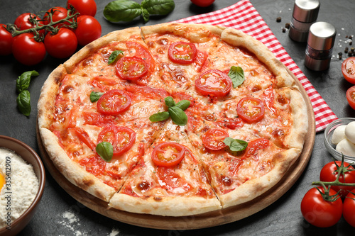Delicious pizza Margherita and ingredients on dark grey table