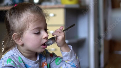 Baby girl eating. Slow motion video of child holding spoon and eating soup.
