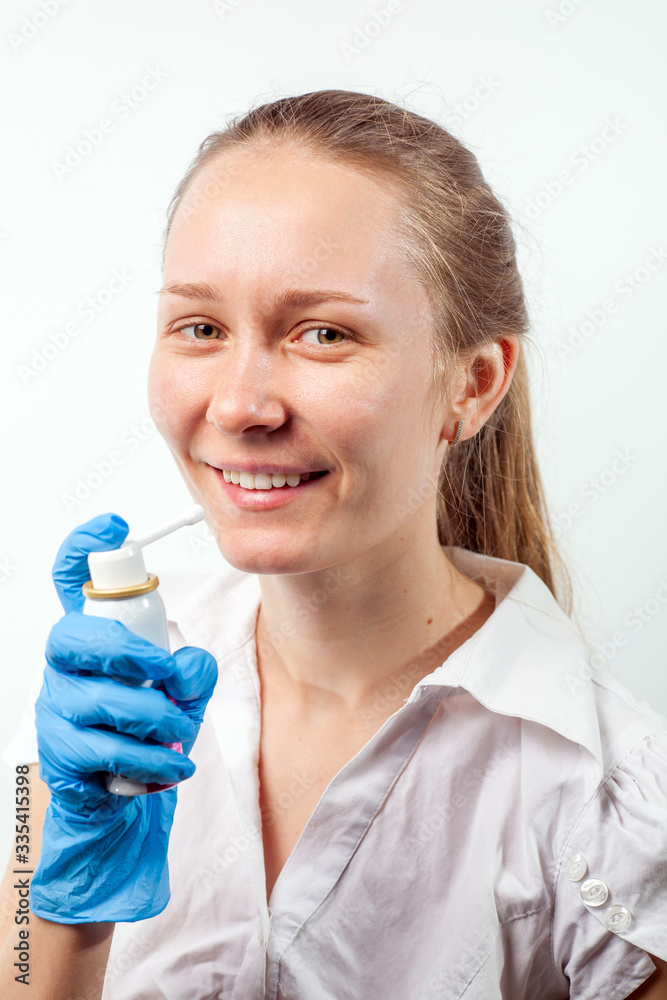 Young and attractive doctor with a throat spray isolated on white Young and attractive doctor with a throat spray isolated on white