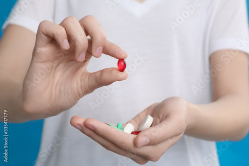Young woman with vitamin pills on blue background  closeup