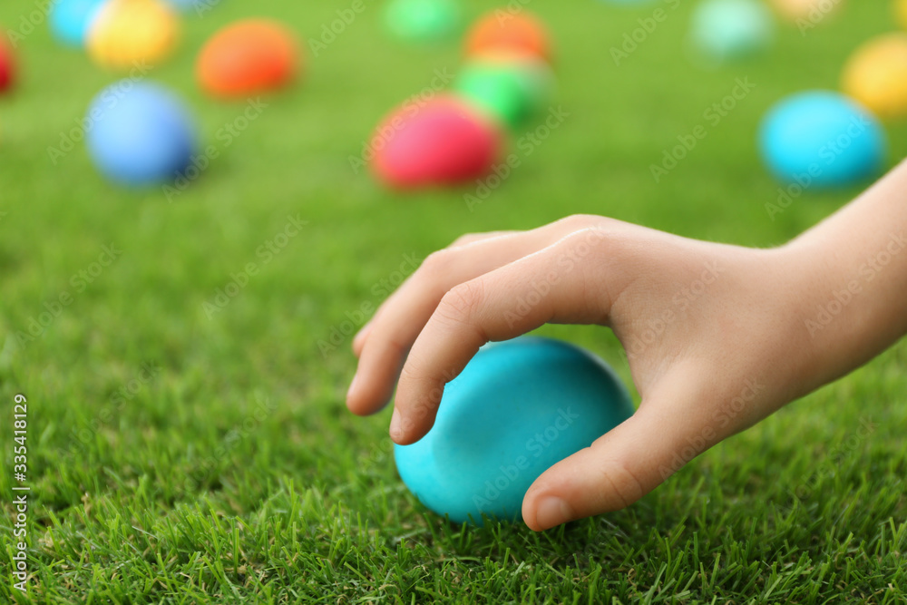 Little child taking Easter egg from green grass, closeup Little child taking Easter egg from green grass, closeup