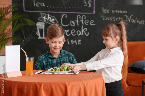 Cute little waiter serving ...