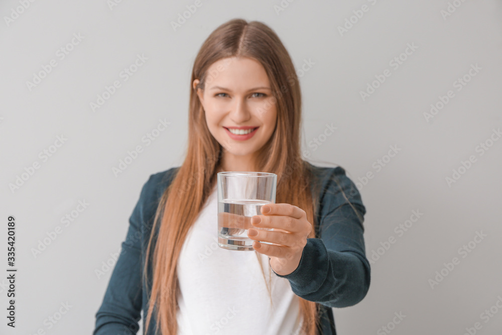 Beautiful young woman with glass of water on light background Beautiful young woman with glass of water on light background