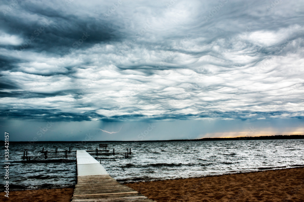 Ominous Storm Clouds With Lightning Over Choppy Lake With Dock