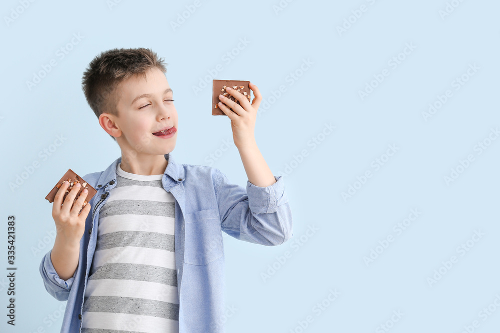 Cute little boy with chocolate on color background Cute little boy with chocolate on color background