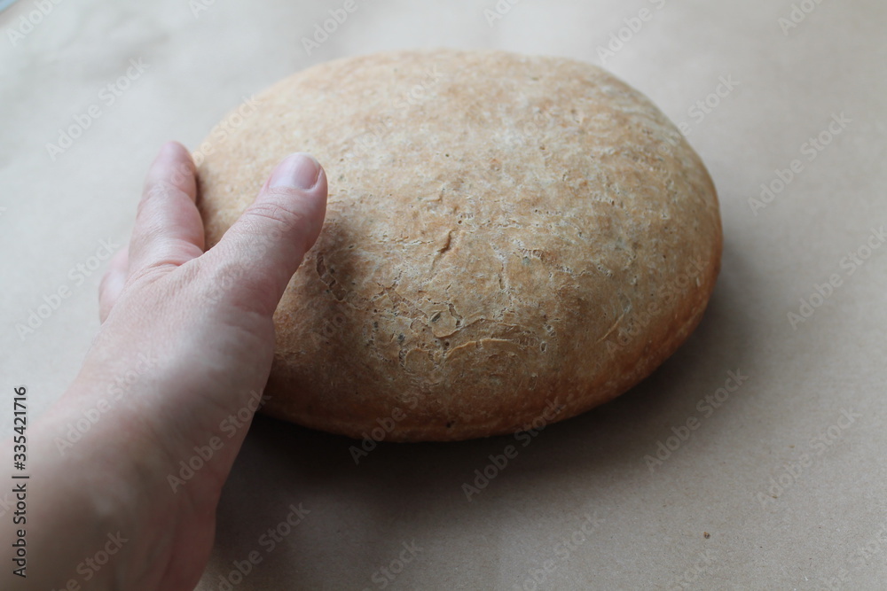 A woman's hand reaches for the freshly baked bread. The concept of cooking delicious and healthy food at home. A woman's hand reaches for the freshly baked bread. The concept of cooking delicious and healthy food at home.