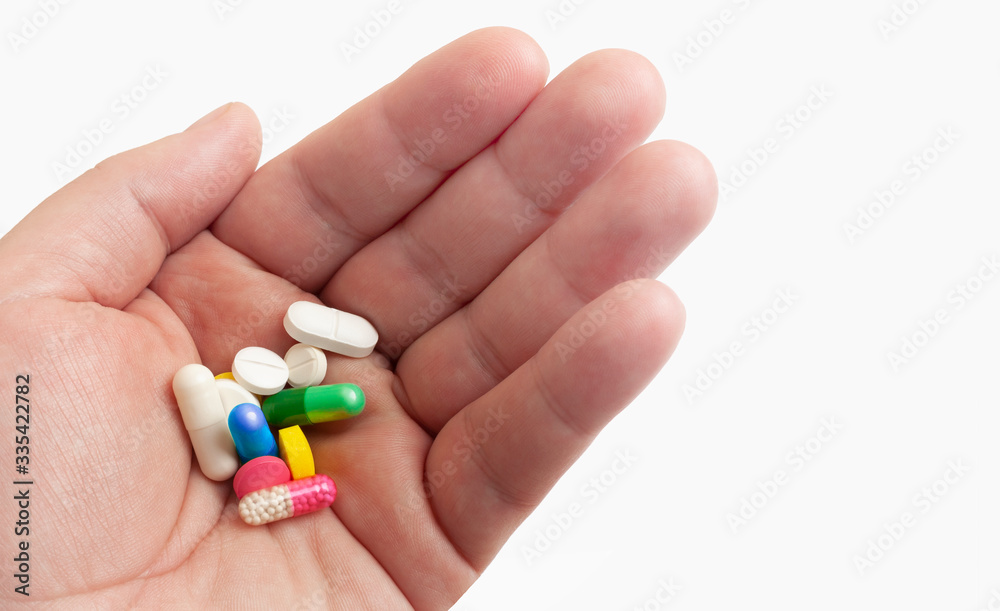 Man holds medicine pills in hand before taking them Man holds medicine pills in hand before taking them