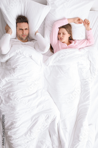 Young irritated man in bed ...