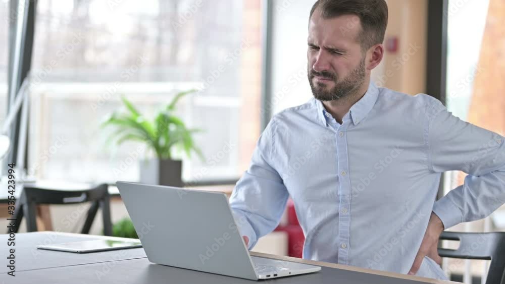 Tired Young Man having Back Pain in Office Tired Young Man having Back Pain in Office