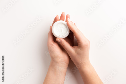 Fototapeta Naklejka Na Ścianę i Meble -  Women hands with container of cream isolated, on white background. Flat lay, top view, copy space. Organic cosmetic concept.