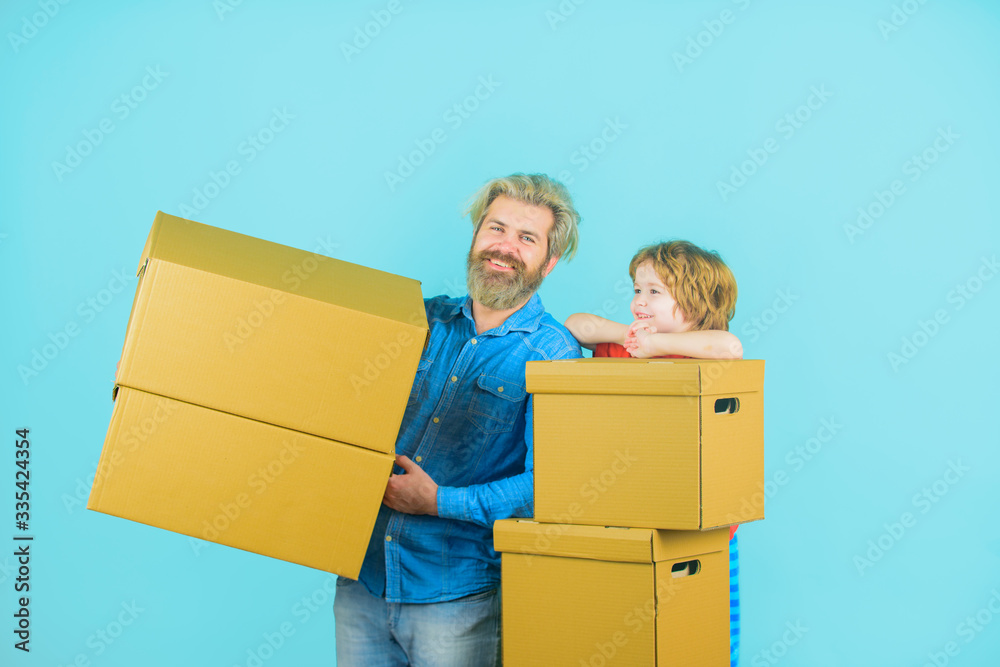 Prepare for moving. Packaging. Father and son with boxes. Family concept. Happy son and father with cardboard box. Moving concept. Son helps his father carrying cardboard boxes. Prepare for moving. Packaging. Father and son with boxes. Family concept. Happy son and father with cardboard box. Moving concept. Son helps his father carrying cardboard boxes.