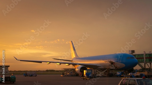 Airport ground crew loading cargo and luggage on a commercial aircraft at dawn.