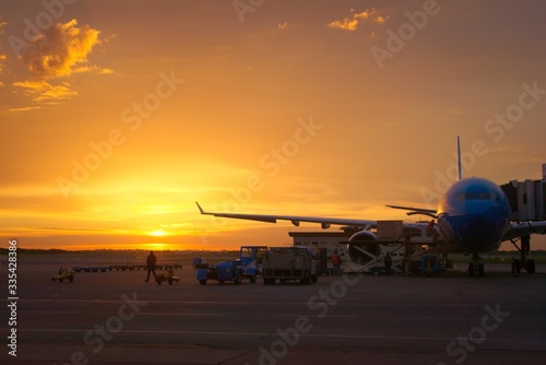 Wallpaper Mural Airport ground crew loading cargo and luggage on a commercial aircraft at dawn. Torontodigital.ca