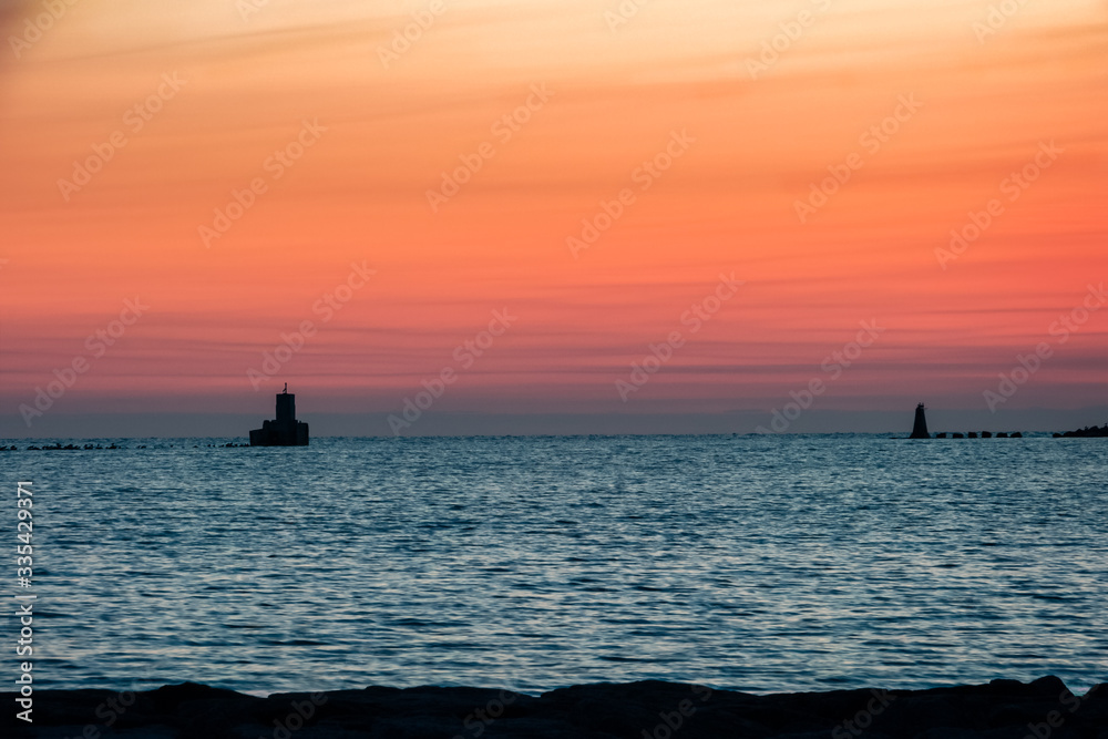 A barrier breakwater wall at the entrance to a port at sunset-sunrise