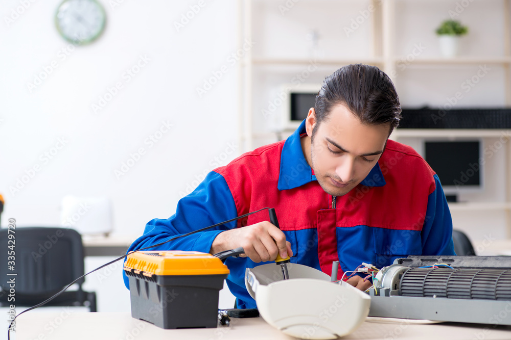 Young repairman repairing air-conditioner at warranty center