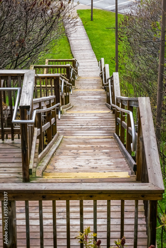 Fototapeta Naklejka Na Ścianę i Meble -  Large wooden staircase with  hand rail leading down into a park, springtime