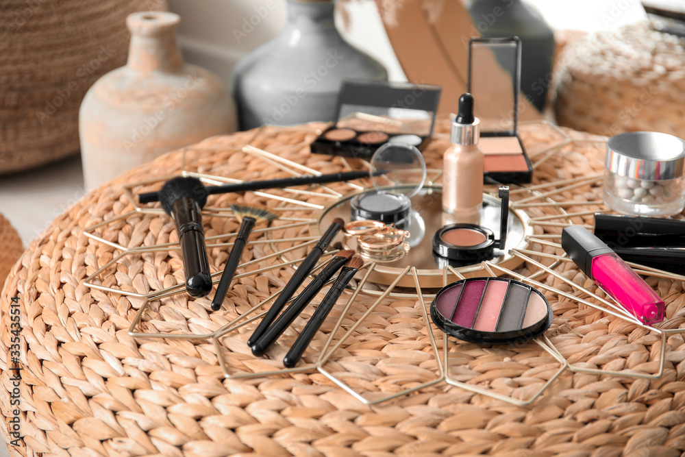 Set of decorative cosmetics of makeup artist on pouf in room Set of decorative cosmetics of makeup artist on pouf in room