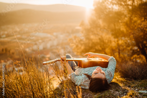 Young guitarist playing acoustic guitar and looking to sunset.Searching inspiration.Music creator.New artist in good mood.Musical talent.Smiling young woman singing and playing acoustic guitar.
