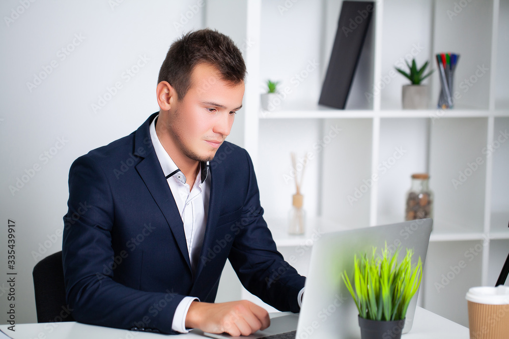 Handsome young worker working in a company office with documents and a laptop Handsome young worker working in a company office with documents and a laptop