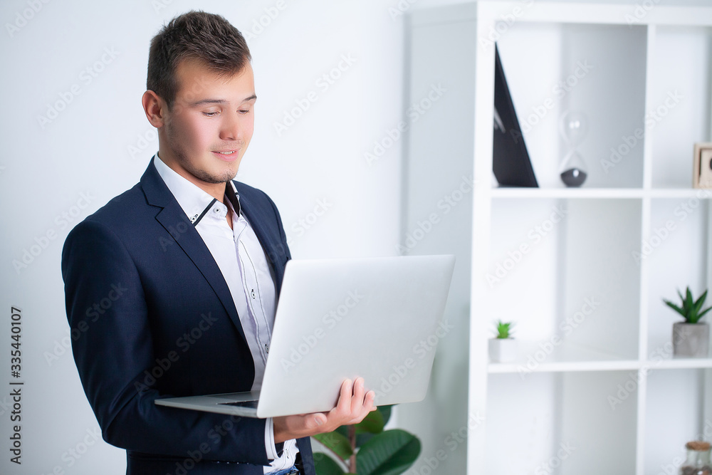 Handsome young worker working in a company office with documents and a laptop Handsome young worker working in a company office with documents and a laptop