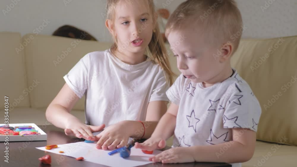 Two child, old sister and little brother playing with plasticine at home. Two child, old sister and little brother playing with plasticine at home.