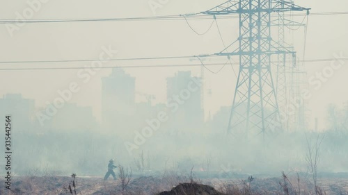 Forest fire with smoke near the city. Burning grass among power poles against the background of buildings and houses. Air pollution and ecology. Fires caused by drought and climate change