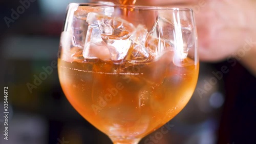 The process of making cocktail aperol spritz. pours orange liquor into glass