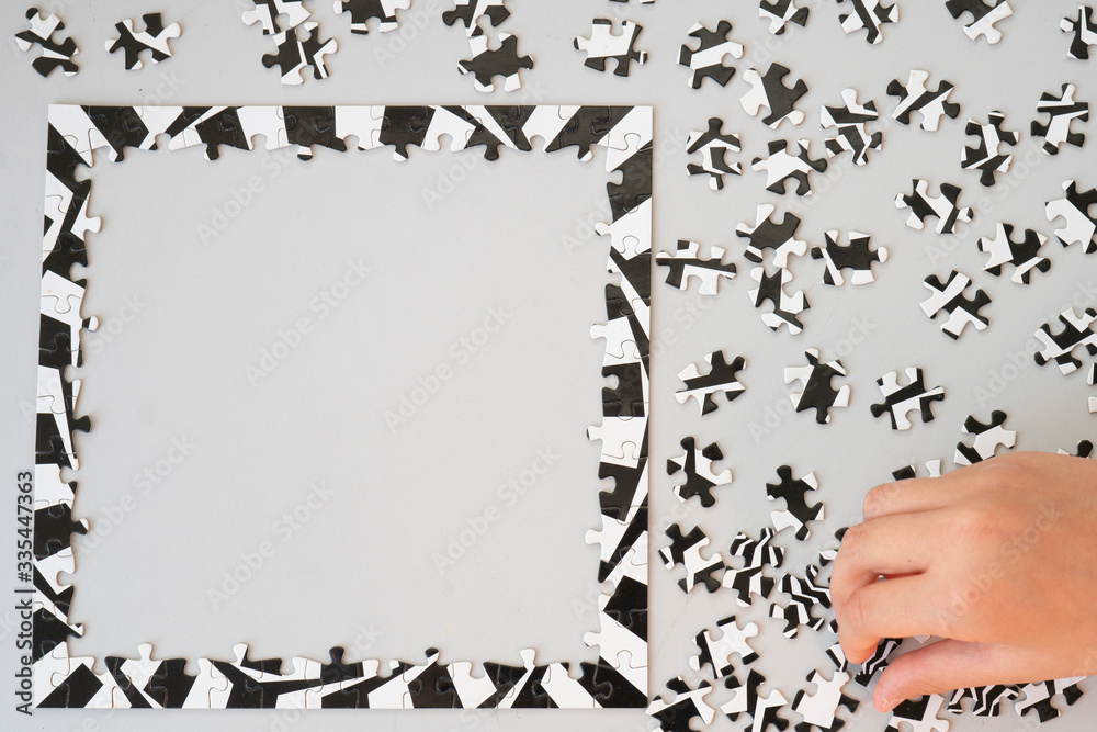 Close Up of Person Working on Black and White Puzzle From Above