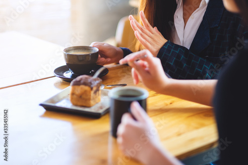 Closeup image of women enjoyed eating dessert and drinking coffee together in cafe