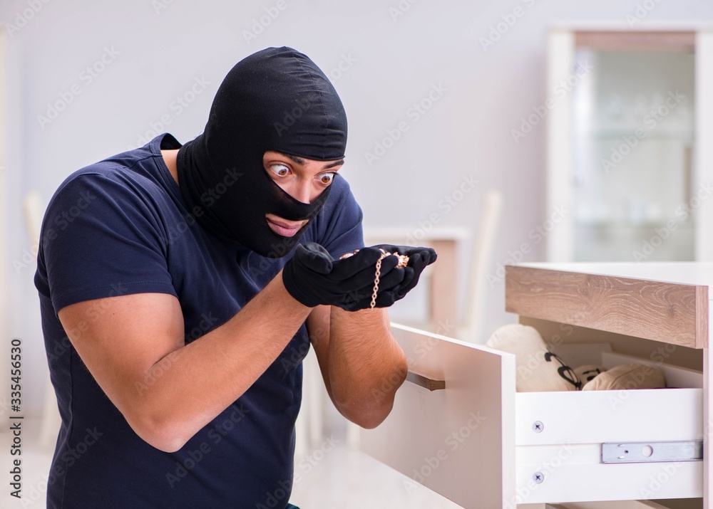Robber wearing balaclava stealing valuable things Robber wearing balaclava stealing valuable things