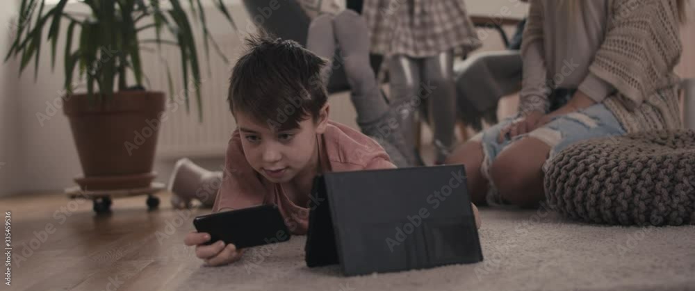Boy playing games on smartphone enjoying family time during coronavirus covid 19 pandemic outbreak wellbeing staying home in isolation