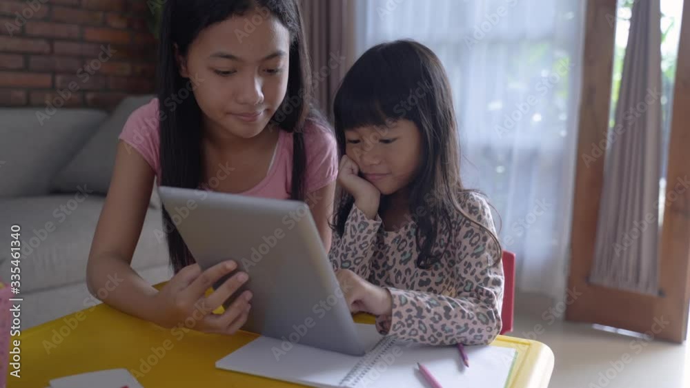 upset kid while studying at home with her big sister at home. bored learning