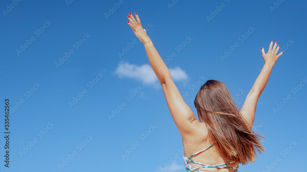 On the beach. Beautiful woman raises hands to heaven as a sign of freedom or victory and in the background a fantastic landscape. Concept of: breathing, freedom, journey, life, love. On the beach. Beautiful woman raises hands to heaven as a sign of freedom or victory and in the background a fantastic landscape. Concept of: breathing, freedom, journey, life, love.