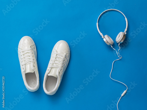 White headphones and white sneakers on a blue background.