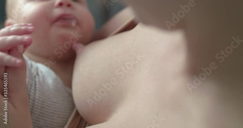 Cute baby's hand in mother's hand at chest during breastfeeding photo