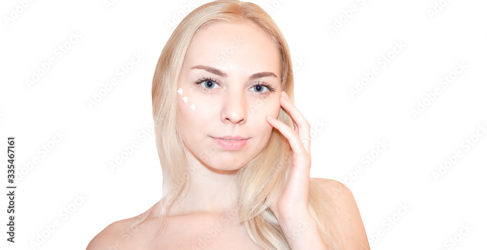 Beautiful face of young woman with cosmetic cream on a cheek. Skin care concept. Closeup portrait isolated on white. Attractive tender woman with perfect skin.