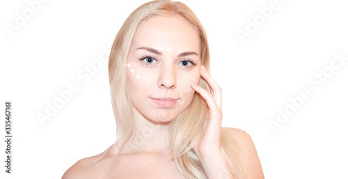 Beautiful face of young woman with cosmetic cream on a cheek. Skin care concept. Closeup portrait isolated on white. Attractive tender woman with perfect skin.