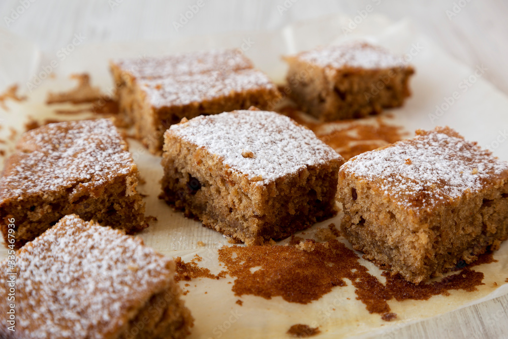 Homemade Tasty Applesauce Cake on a white plate on a white wooden surface, side view. Close-up.