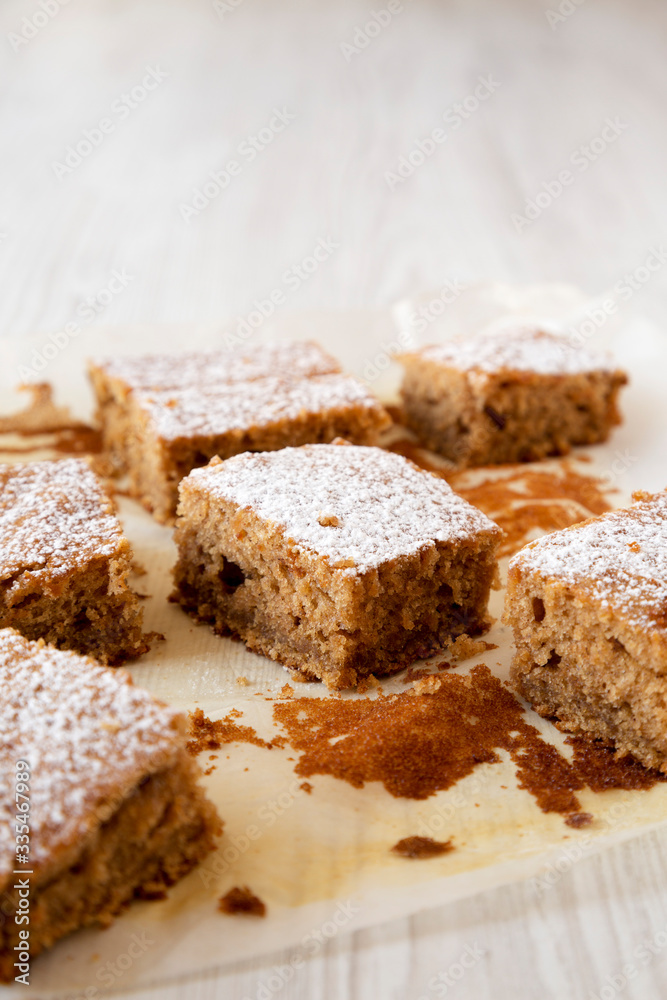 Homemade Tasty Applesauce Cake on a white plate on a white wooden background, side view. Copy space.