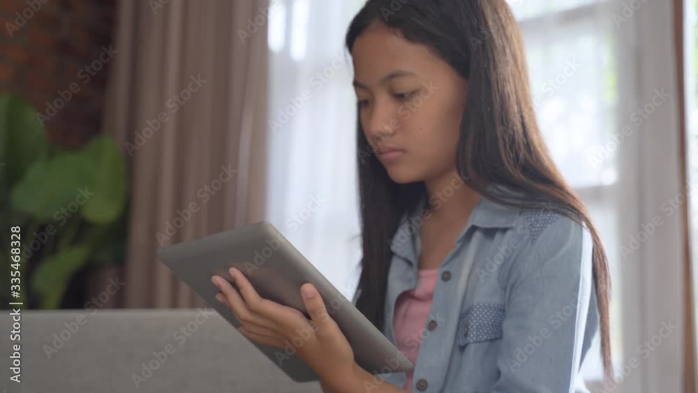 serious looking teen using tablet at home while sitting on a couch serious looking teen using tablet at home while sitting on a couch