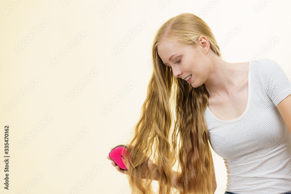 Fototapeta premium Blonde girl brushing her long hair