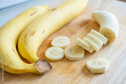 Slices or chopped yellow banana on cutting board.